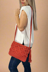 Model is wearing a red colored cotton macrame crossbody with a tassel detail. 