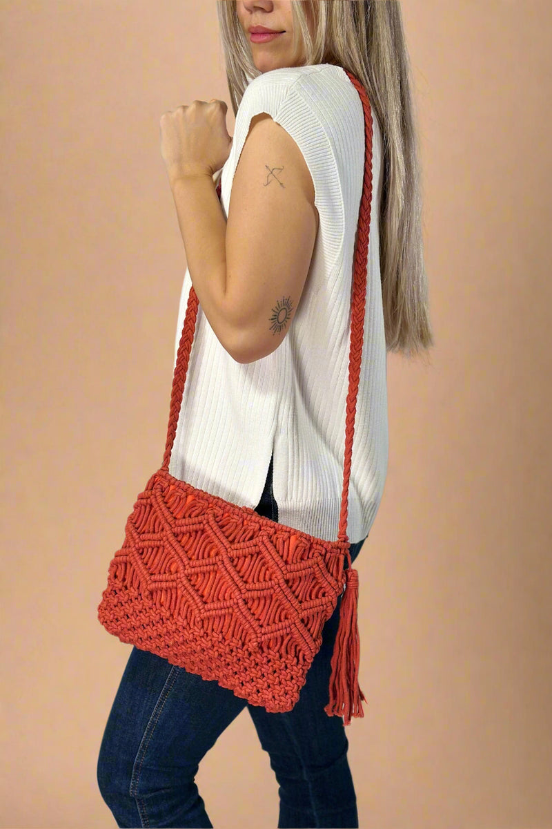 Model is wearing a red colored cotton macrame crossbody with a tassel detail. 