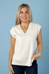 Model is wearing a soft white ribbed knit sleeveless sweater top with a v neckline. 