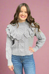 A grey knit sweater with ruffle details.