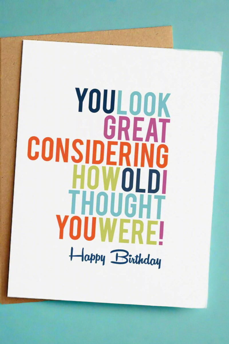 A simple white greeting card with multi-colored text that reads ‘You look great considering how old I thought you were! Happy birthday’.