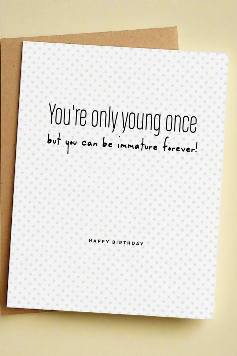 A simple white greeting card with small grey polkadots and black text that reads ‘You’re only young once but you can be immature forever! Happy Birthday’.