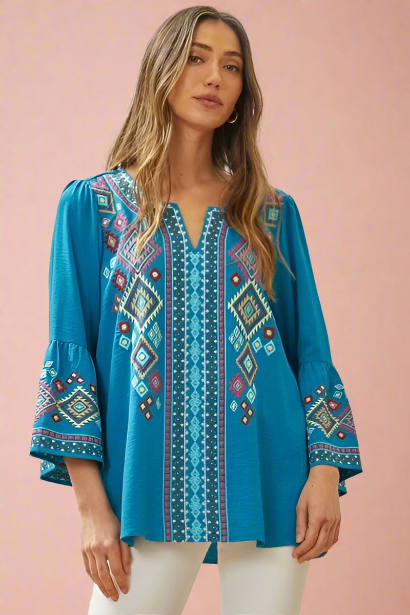 A teal blouse with geometric embroidery and bell sleeves.