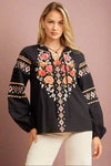 A black long sleeve floral embroidered blouse. This light weight blouse has a tie neck and cinched sleeves.