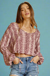 A open neck, shimmer top in a magenta snake print. It is lightweight with balloon sleeves.