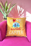 A yellow, square accent pillow that has home sweet camper written on the front.