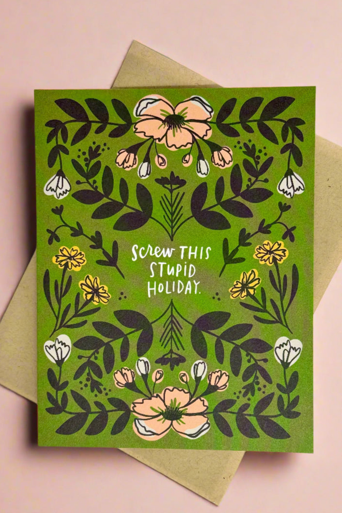A green card with floral detail with words “Screw this stupid holiday.”