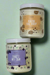 An image of the 16 oz Punny Candles in the scents Raisin The Roof and That’s My Jam.