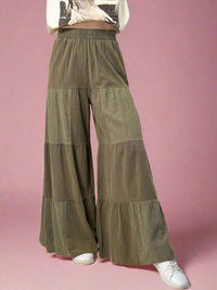 Model is wearing olive colored tiered pants with an elastic waist and eyelet patchwork detailing. 