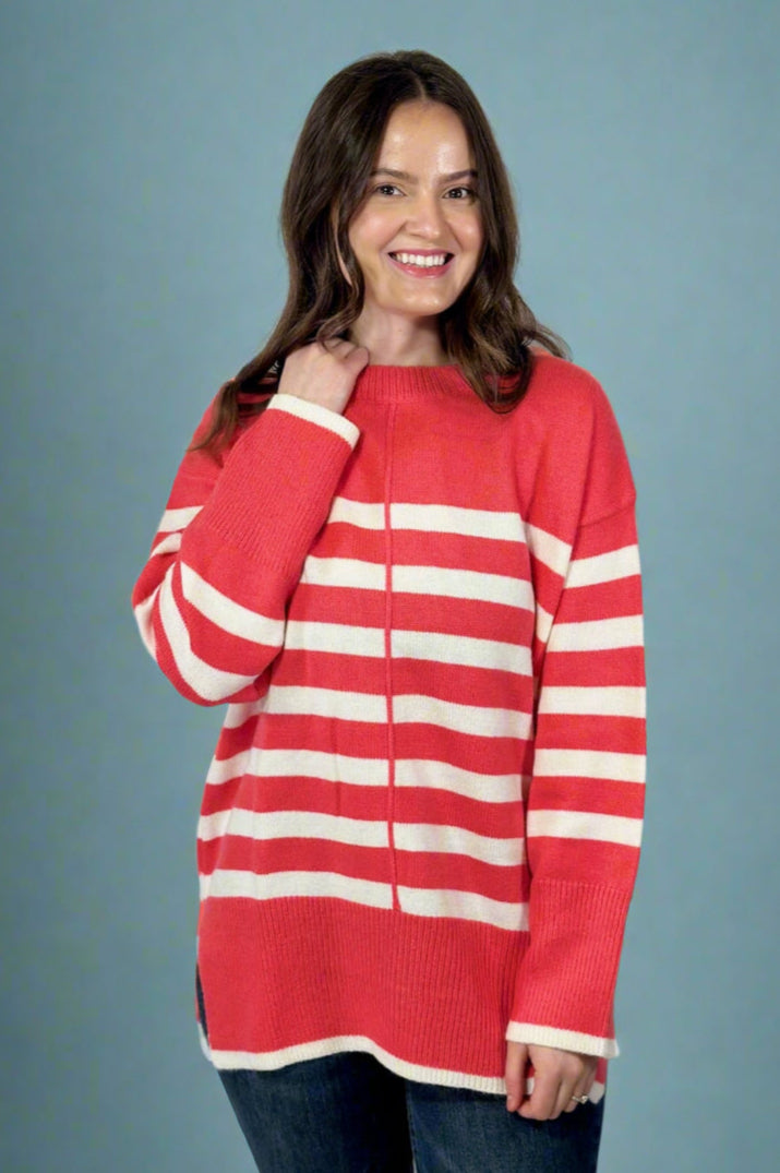 Model is wearing a striped oversized crew neck sweater in a vibrant pink and white color way.