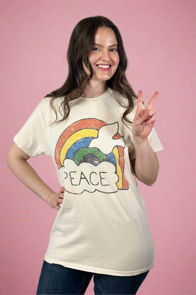 Model is wearing a cream colored vintage tee with a colorful peace graphic with a dove and a rainbow. 