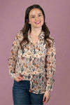 Model is wearing a sheer lightweight button up top featuring a funky western inspired print. 