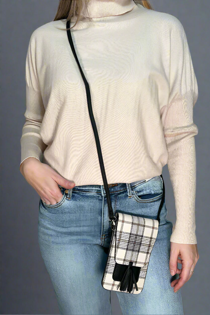 A cream and black plaid print small cross body bag. It has a close flap and tassel detail.