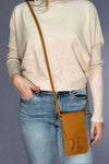A mustard color, small cross body bag. It has a close flap and tassel detail.