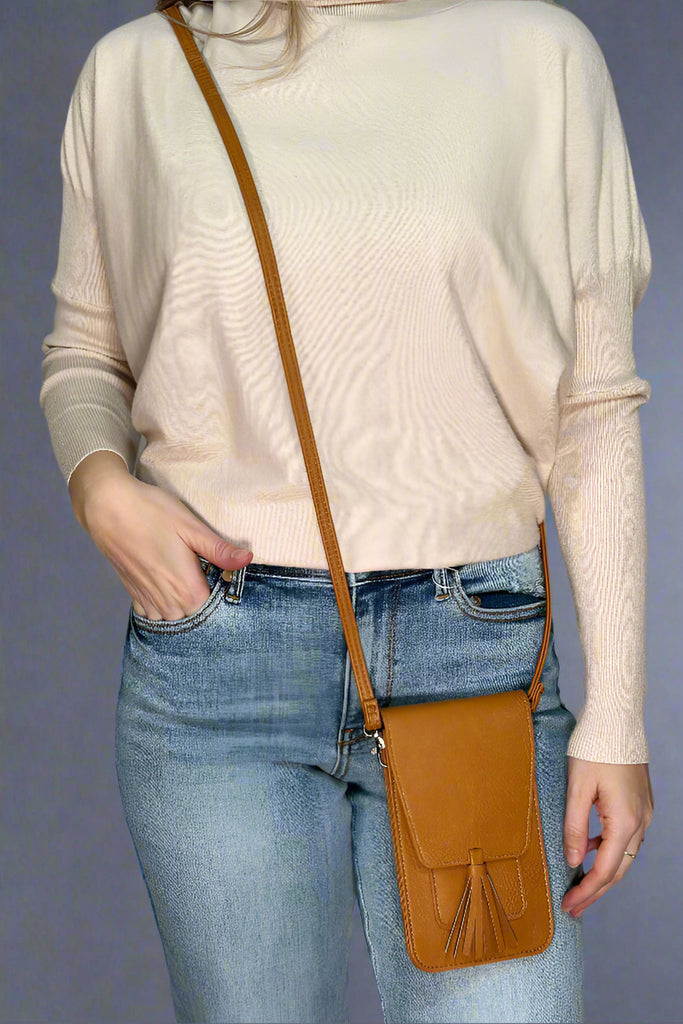 A mustard color, small cross body bag. It has a close flap and tassel detail.