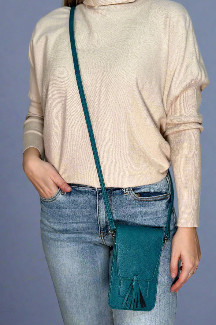 A teal, small cross body bag. It has a close flap and tassel detail.