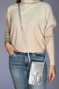 A shiny silver, small cross body bag. It has a close flap and tassel detail.