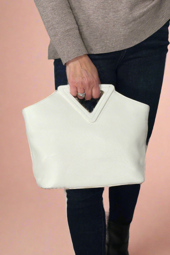 Women’s handbag in white with triangular handle and removable adjustable crossbody strap.