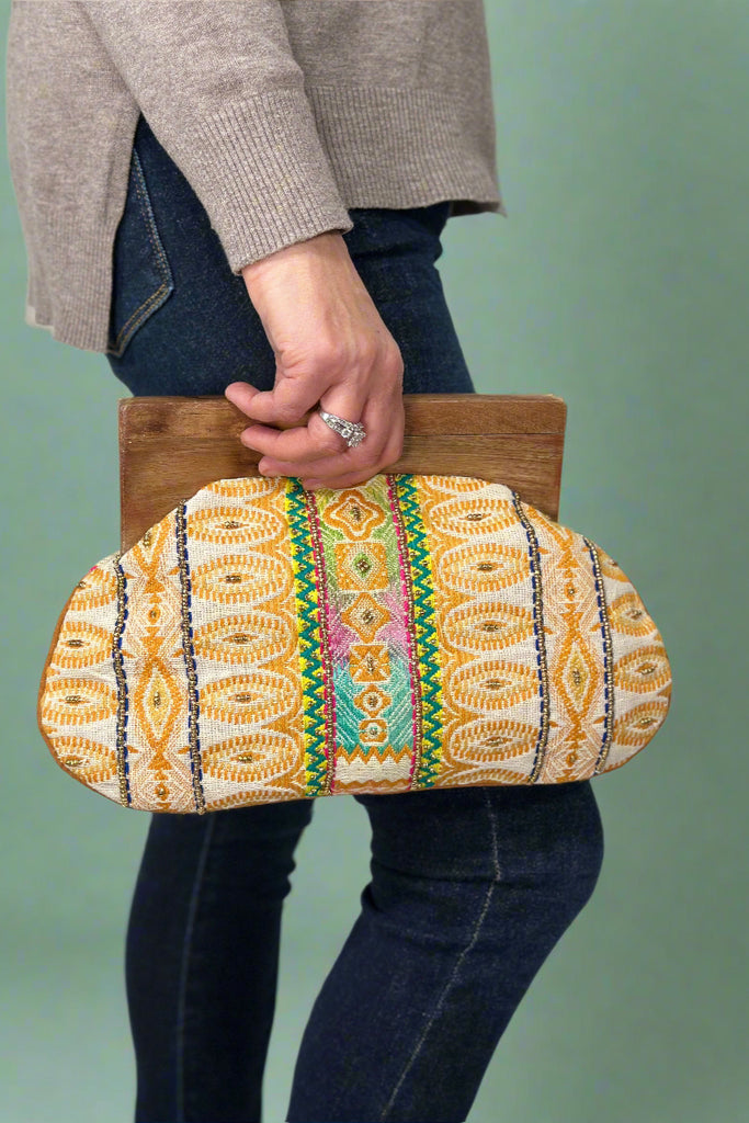 A brightly woven beaded clutch with tribal print and wooden handle.