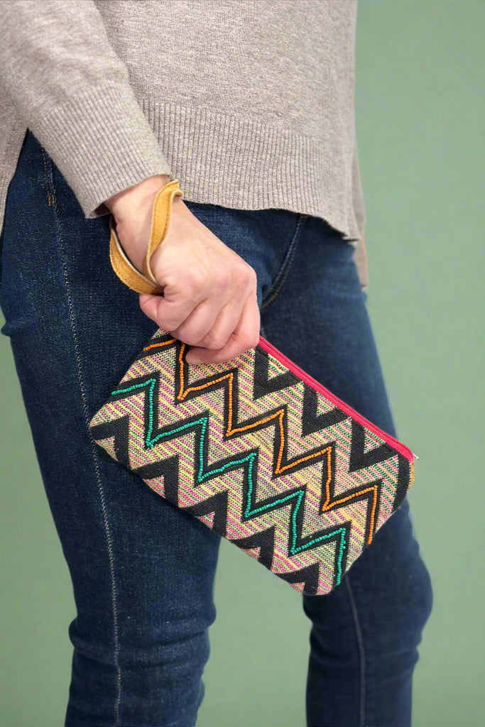 Model is holding a zig zag printed wristlet with beaded detailing. 