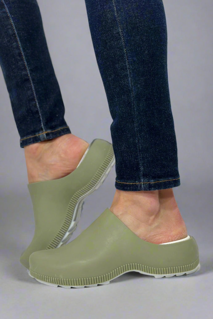 Model is wearing green rubber slip on clogs.