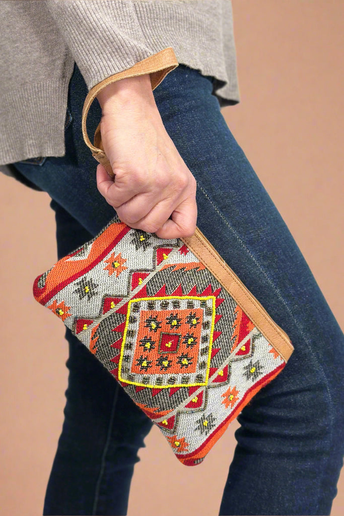 Model is holding a small colorful beaded wristlet. 