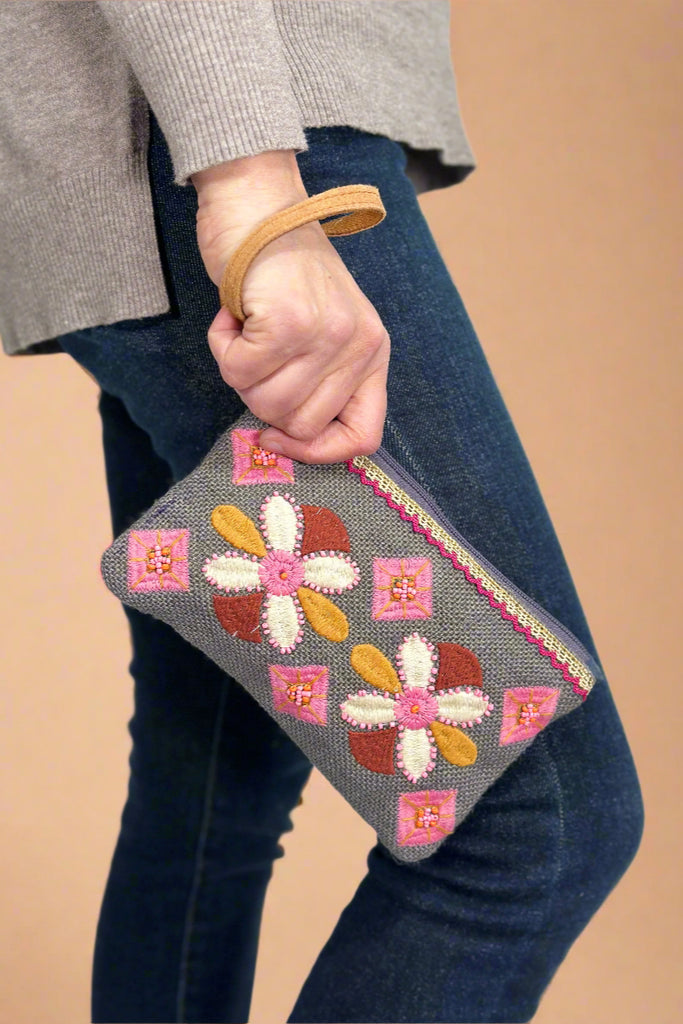 Model is wearing a floral embroidered wristlet. 