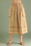 Model is wearing a tan cargo style midi skirt with exposed seam details and an adjustable tie waist.