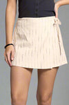Model is wearing a striped cream and black colored skort with pockets and a tie waist. 