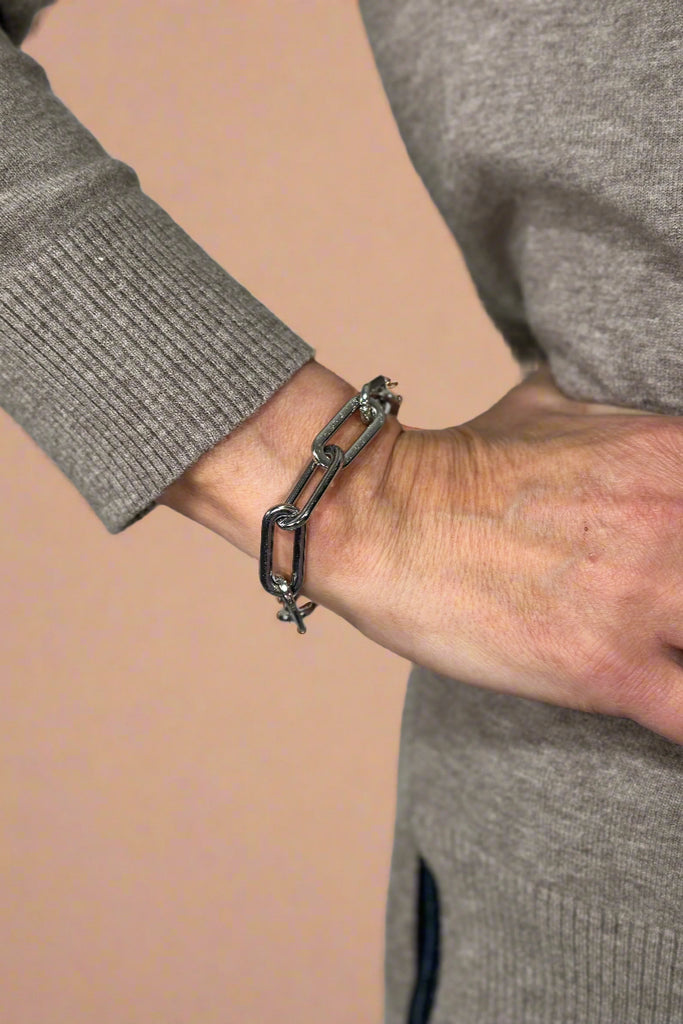 Model is wearing a silver chain link bracelet. 