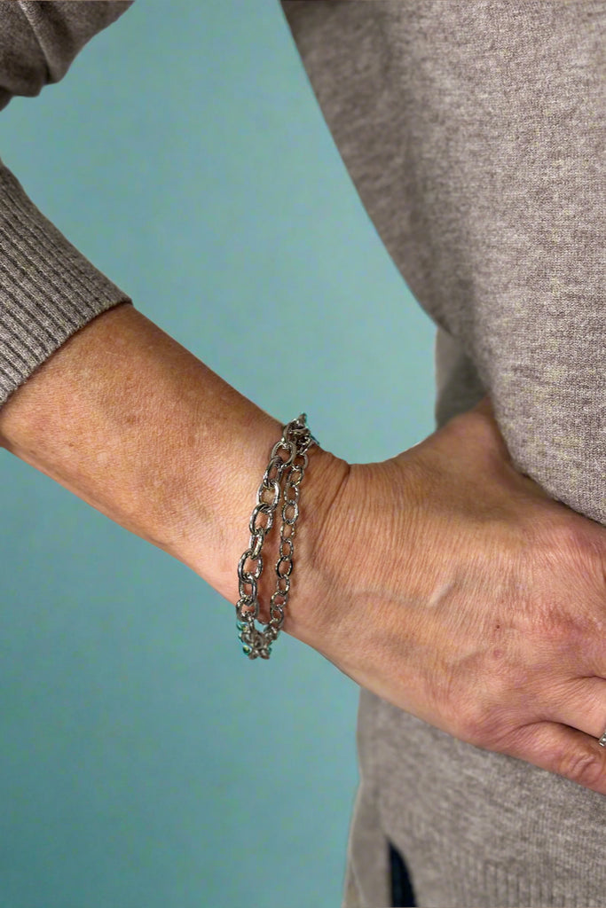 Model is wearing a double layer silver chain bracelet. 