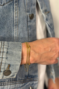 Model is wearing a gold wrap bracelet that doubles as a necklace.
