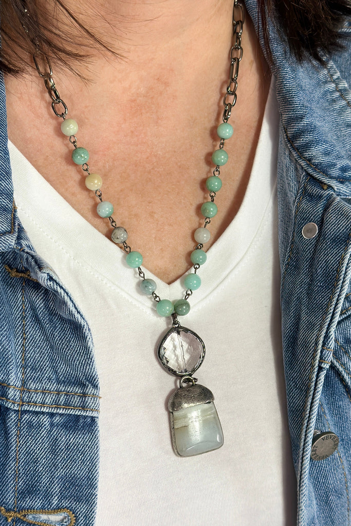 Dark grey beaded chain link necklace with crystal and stone pendant.