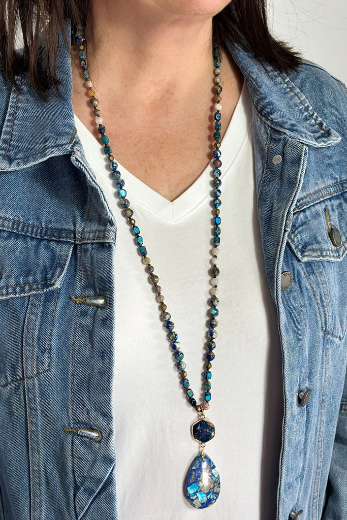 A long blue stone beaded necklace with large blue stone teardrop pendant.