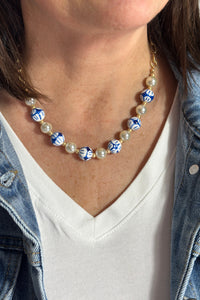 Short gold chain necklace with faux pearl, and blue and white round beaded front.