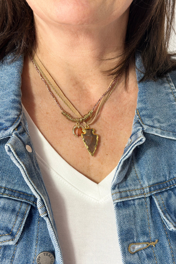 Short stackable necklaces. One gold and leather chain with arrowhead pendant trimmed in gold. Second necklace is metallic thread with gold beads and carnelian stone pendant.