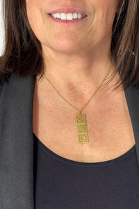 Short gold necklace featuring stacked mid century modern breeze blocks pendant.