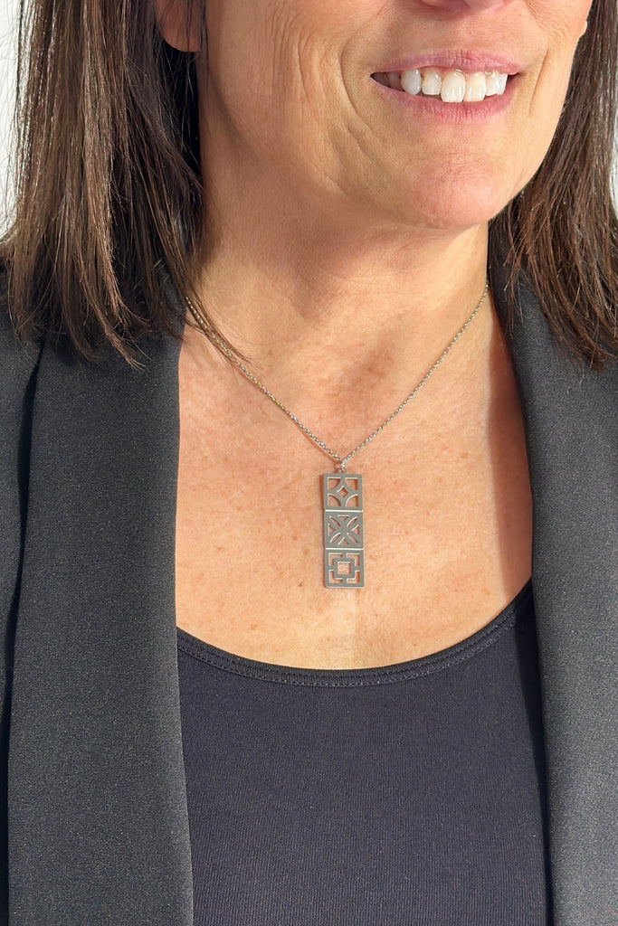 A silver plated chain necklace with stainless steal stacked breeze block pendant.