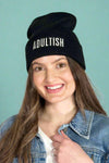 Model is wearing a black beanie that has the word "ADULTISH" embroidered across the front in white lettering. 