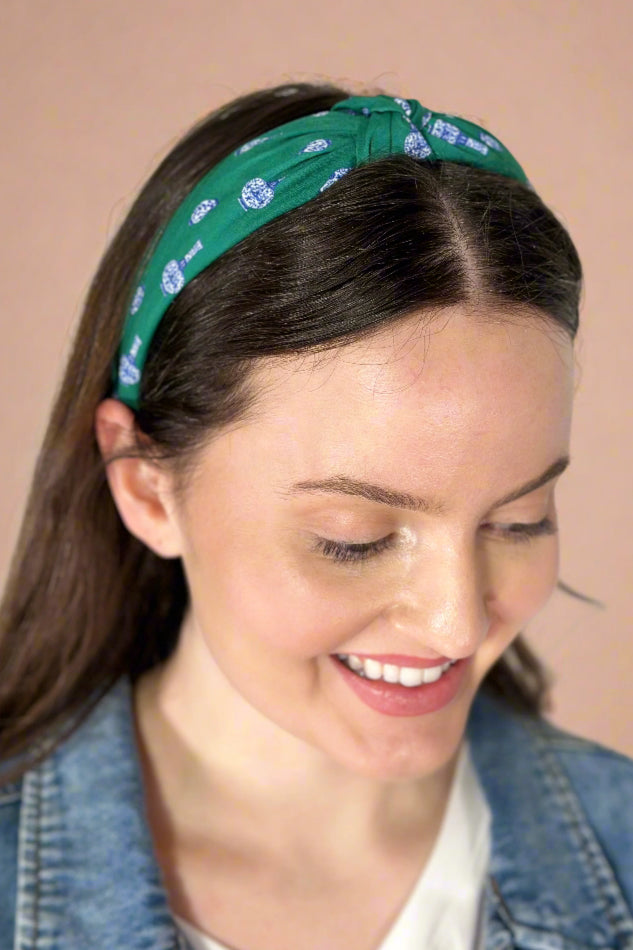 Model is wearing a green knotted headband with ginger jars printed on it. 