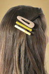 Model is showing off three colored hair clips.