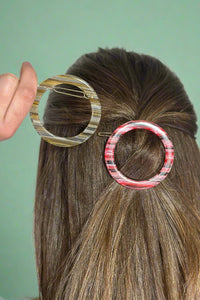 Model is showing off two round hair clips. 