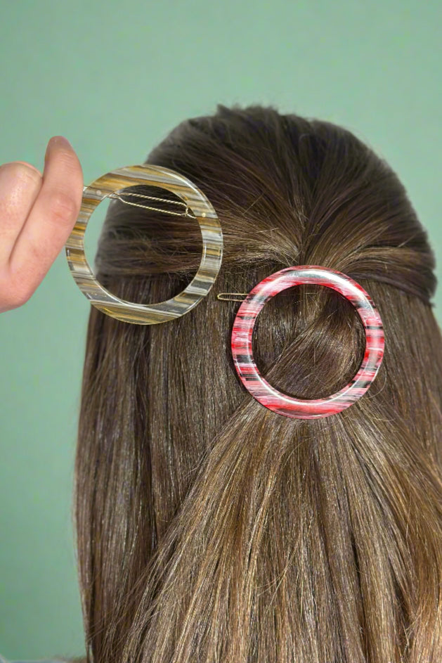 Model is showing off two round hair clips. 