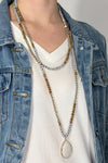 Model is wearing a beaded wrap necklace with a teardrop pendant. 