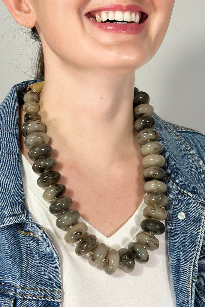 Model is wearing a large beaded collar length necklace. 