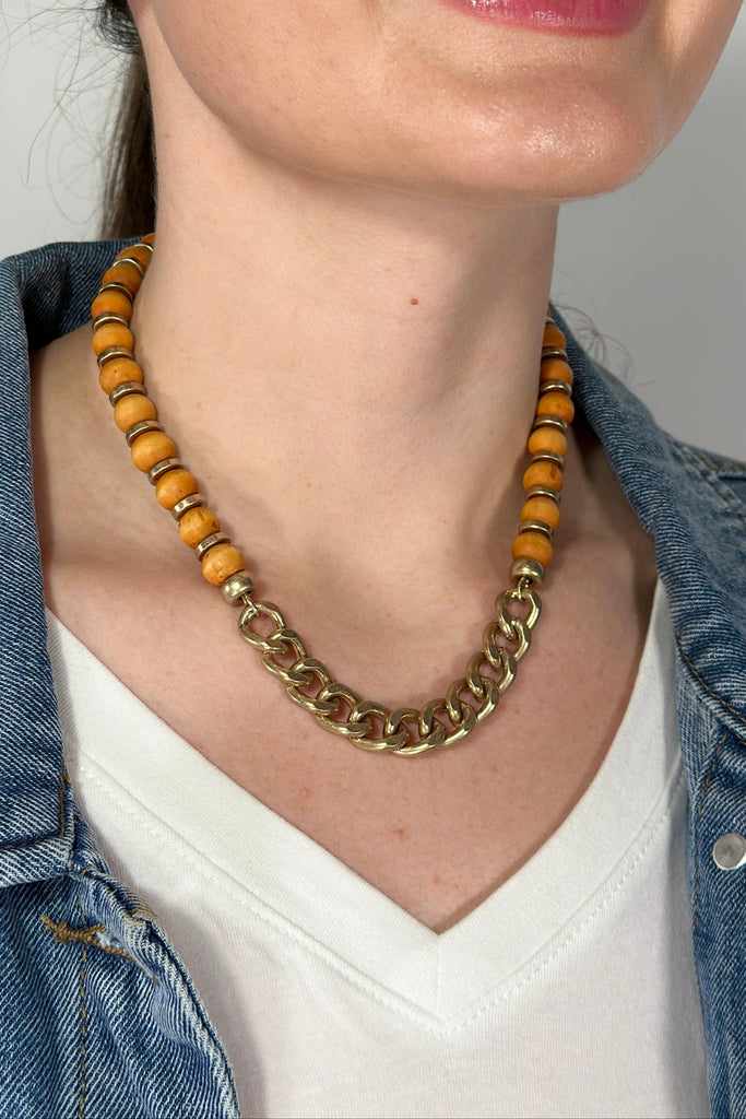 Model is wearing a collar length necklace with with a mix of beads and chain links. 