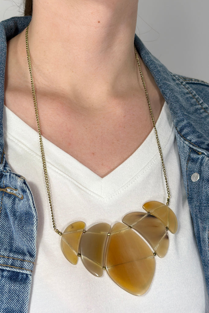 Model is wearing a statement necklace with a pendant made from eye of the tiger. 