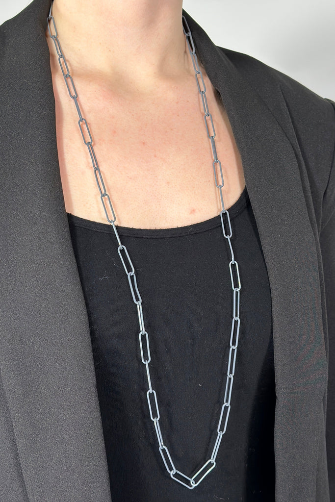 Model is wearing a long grey paper chain link necklace. 