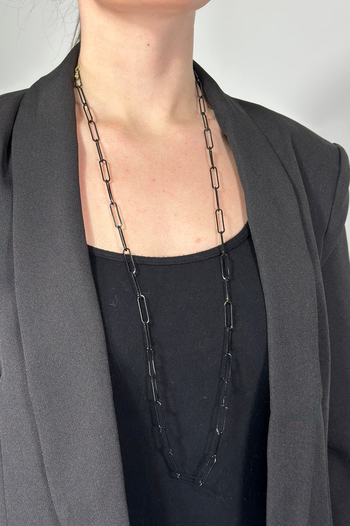 Model is wearing a long black paper chain link necklace. 