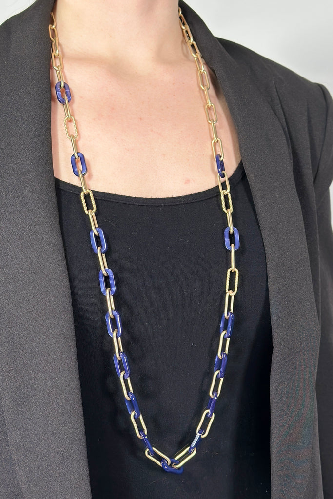 Model is wearing a long chain link necklace with acrylic links alternating.